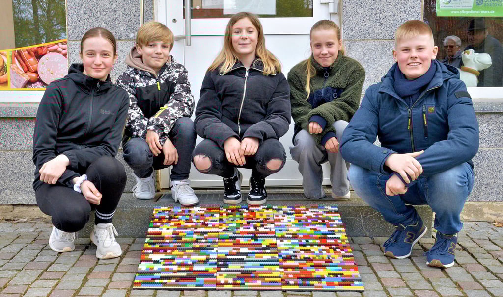Sechstklässler des Hohenmölsener Agricolagymnasiums präsentieren stolz eine ihrer gebauten Auffahrhilfen aus Lego-Steinen, die nun an der Stufe der Osterland-Fleischerei am Altmarkt den Weg ins Geschäft erleichtern soll.