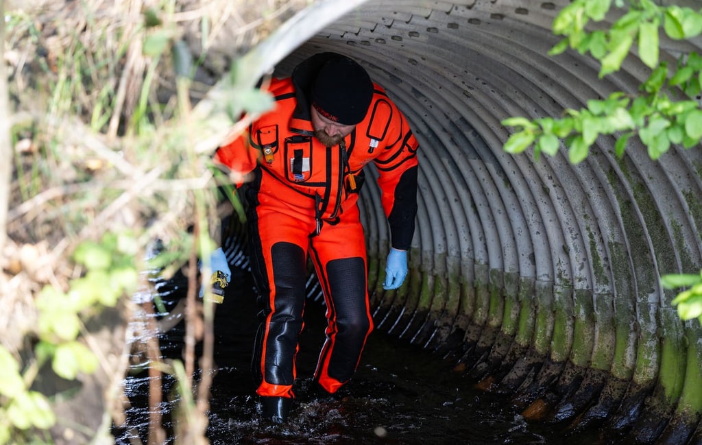 Ehrenamtliche Einsatzkräfte der Feuerwehr durchsuchen Gräben und Rohre.