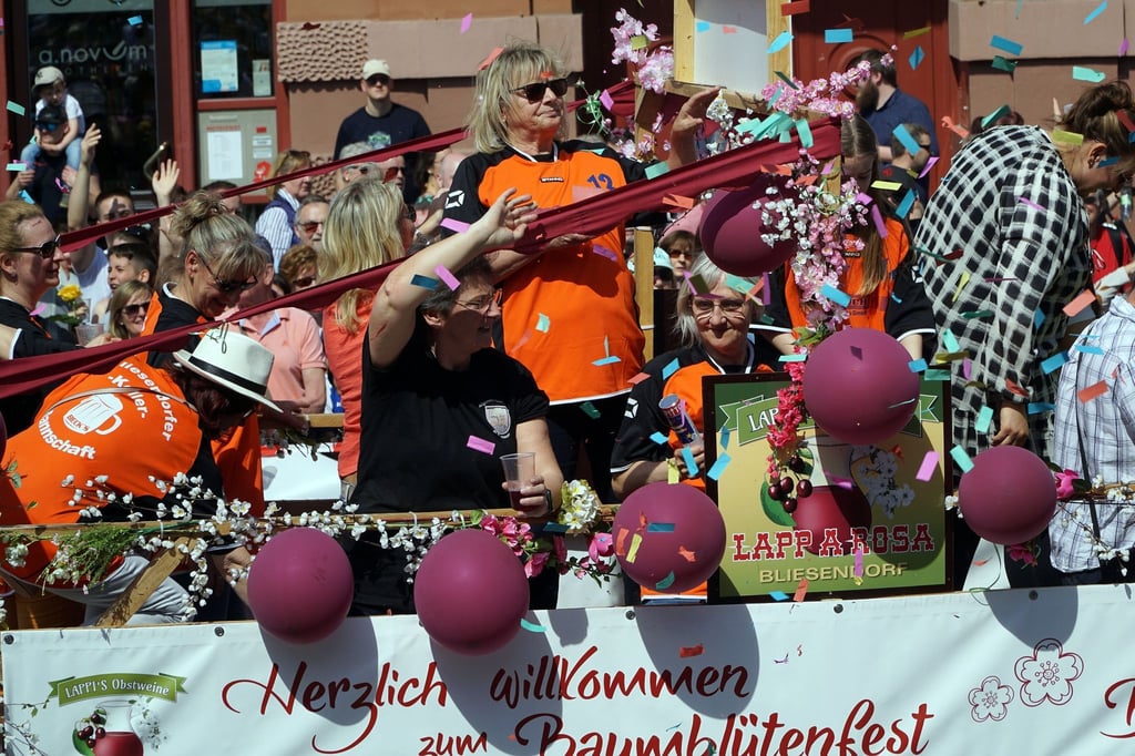 Teilnehmer stehen auf einem Festwagen beim Festumzug von Werders Baumblütenfest.