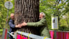 Agrar- und Umweltminister Axel Vogel (Grüne, rechts) und der Generaldirektor der Stiftung Preußische Schlösser und Gärten Berlin-Brandenburg, Martin Vogtherr, zeigen ein „Herz für Bäume“, wie die Station in der Open-Air-Ausstellung „Re:Generation“ heißt.