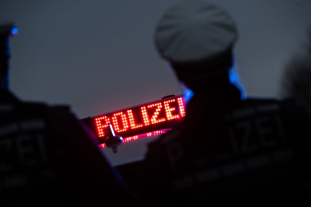 Zwei Polizisten stehen im Rahmen eines Fototermins vor einem Polizeifahrzeug.