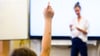 Ein Schüler meldet sich per Handzeichen in einem Klassenraum.