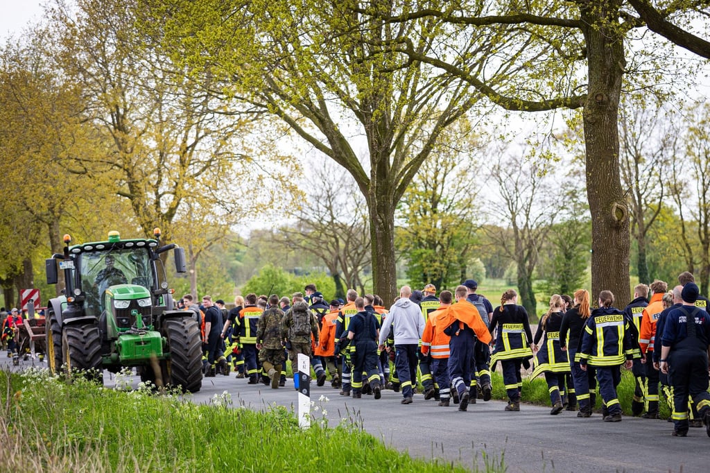 Einsatzkräfte der Feuerwehr gehen eine Straße im Landkreis Stade entlang.