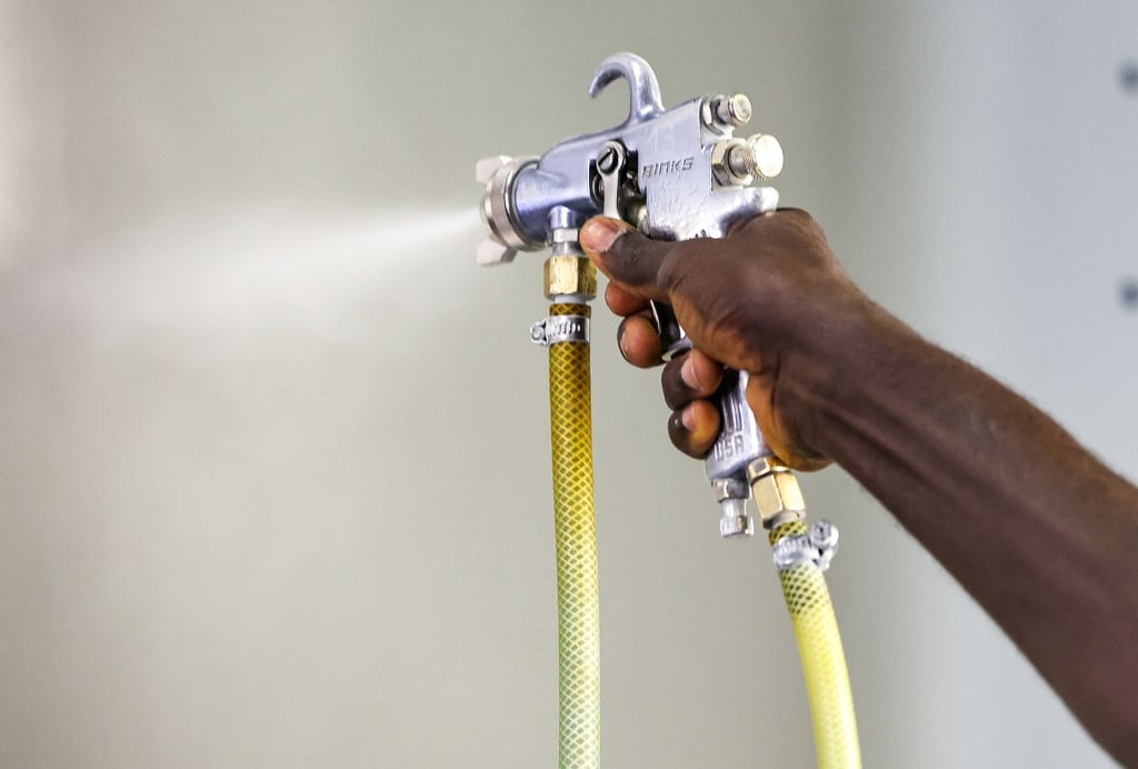 Ein Mitarbeiter aus Gambia bereitet in einem Unternehmen Stahlbleche für die Oberflächenbehandlung vor.