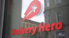 Das Logo und der Schriftzug des Essenslieferdienstes Delivery Hero sind an einer Glasscheibe der Zentrale angebracht.