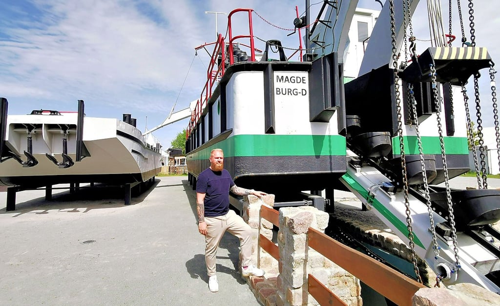 Jens Klein am Eimerkettenbagger „Otter“ (rechts), von dem eine neue Rutsche auf die Schute (links) führt, mit der Schüttgut abtransportiert wurde.
