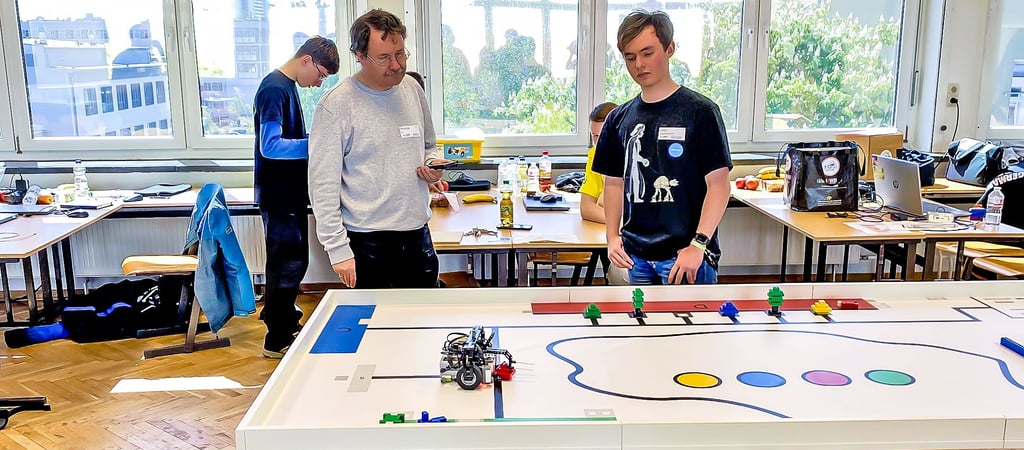 Lukas aus Halle schaut gemeinsam mit einem Juror seinem Roboter dabei zu, wie er ein Legoteil transportiert.