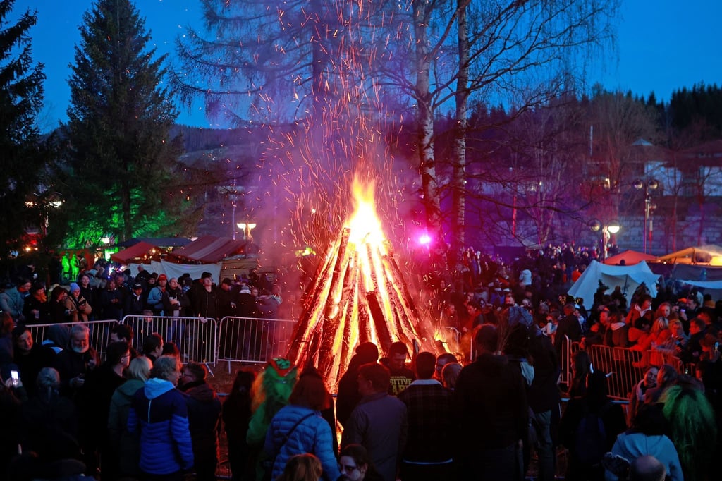 Besucher stehen auf dem Walpurgisfest in Schierke am Feuer.