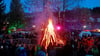Besucher stehen auf dem Walpurgisfest in Schierke am Feuer.