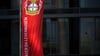 Eine Fahne weht vor der BayArena, dem Stadion des Fußball-Bundesligisten Bayer 04 Leverkusen, und wird dabei von der Sonne angeschienen.