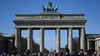 Viele Touristen kommen bei Sonnenschein und blauem Himmel zum Brandenburger Tor, um Erinnerungsfotos zu machen.