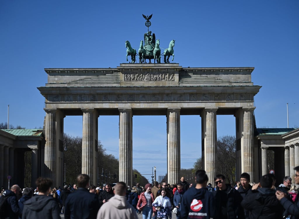 Viele Touristen kommen bei Sonnenschein und blauem Himmel zum Brandenburger Tor, um Erinnerungsfotos zu machen.