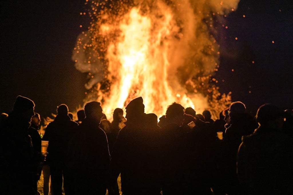 Menschen stehen vor einem Feuer.