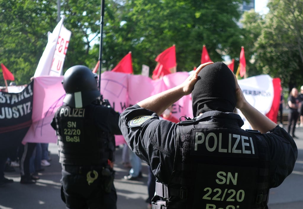 Polizisten setzen bei einer linken Demonstration Schutzhelme auf.