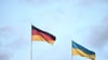 Eine deutsche (l) und eine ukrainische Flagge wehen im Wind.