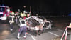 Rettungskräfte stehen am Wrack eines zerstörten Autos nach einem Unfall an einem Bahnübergang.