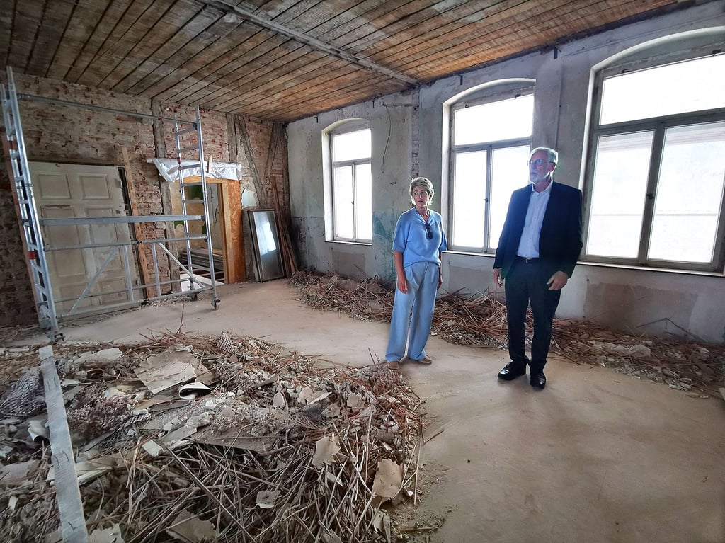 Architektin Sina Stiebler und Kultusminister Rainer Robra stehen inmitten von Schuttbergen. Während im Erdgeschoss des Gebäudes die Bauarbeiten weit fortgeschritten sind, wartet in der ersten Etage noch viel Arbeit.