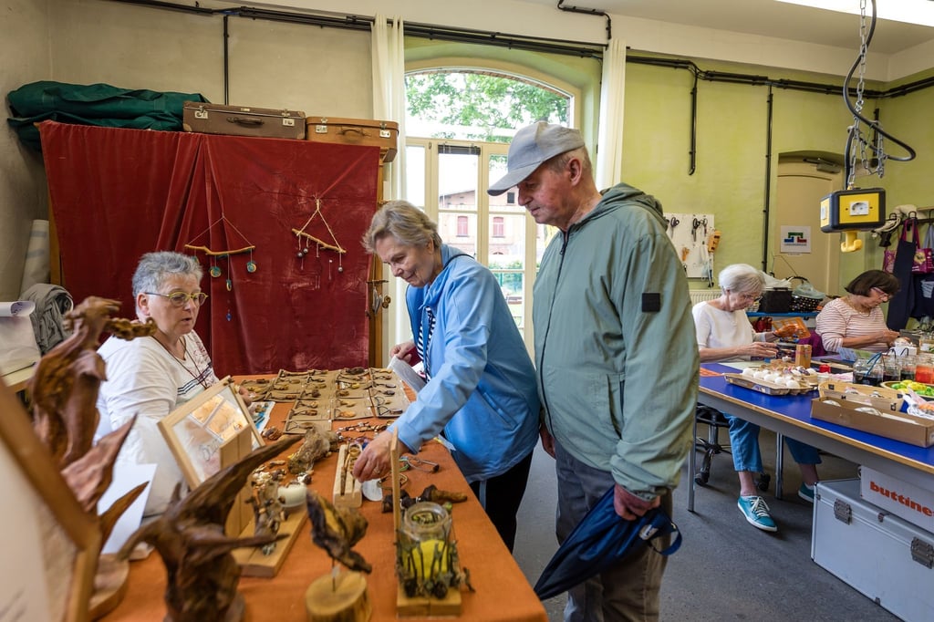 Marlies Klaus (l) unterhält sich im „Gleis 3 - Kulturzentrum Lübbenau“ mit Besuchern über ihren Naturschmuck aus Baumperlen.
