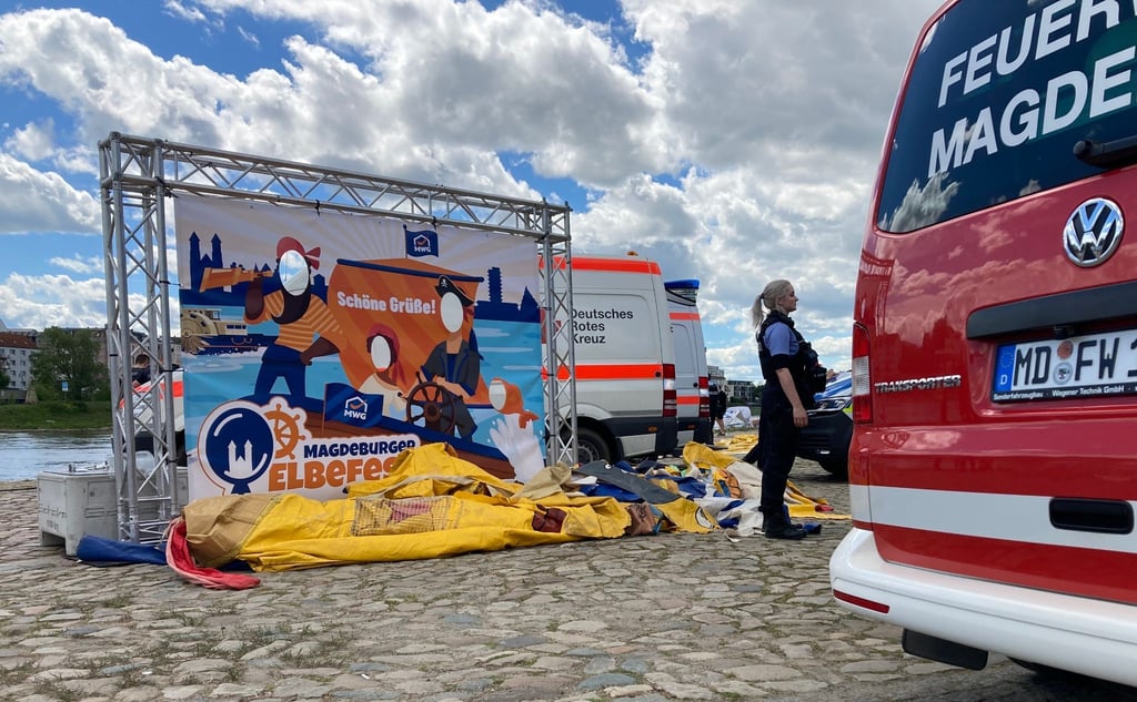 Einsatzfahrzeuge stehen am Elbufer neben einer zusammengefallenen Hüpfburg.