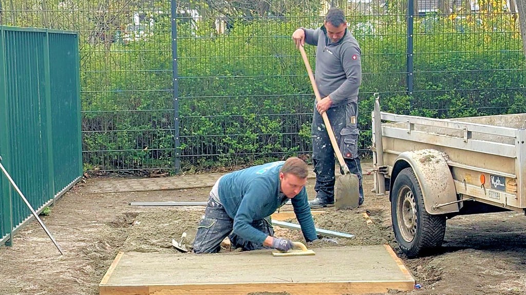 Chris Zabel und ein Kollege kümmern sich auf dem Schulhof der Grundschule Osterweddingen um das Fundament für das Spielgerätehaus.