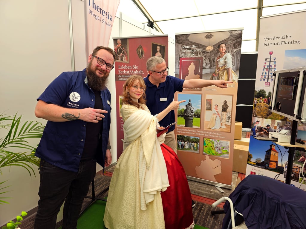 Sophie Auguste Friederike von Anhalt-Zerbst (Vivian Hoffmann) besucht den Stand von Theresia – Pflege & Service GmbH. Geschäftsführer Ralf Zaizek (hinten) und David Laue halten diesen Besuch als Erinnerungsfoto fest.
