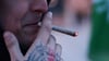 Ein Teilnehmer einer kleinen Mahnwache zur Cannabis-Liberalisierung raucht einen Cannabis-Joint.