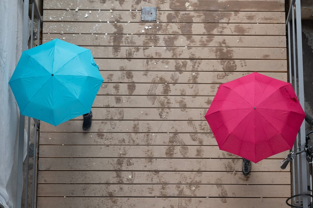 Passanten gehen unter Regenschirmen spazieren.