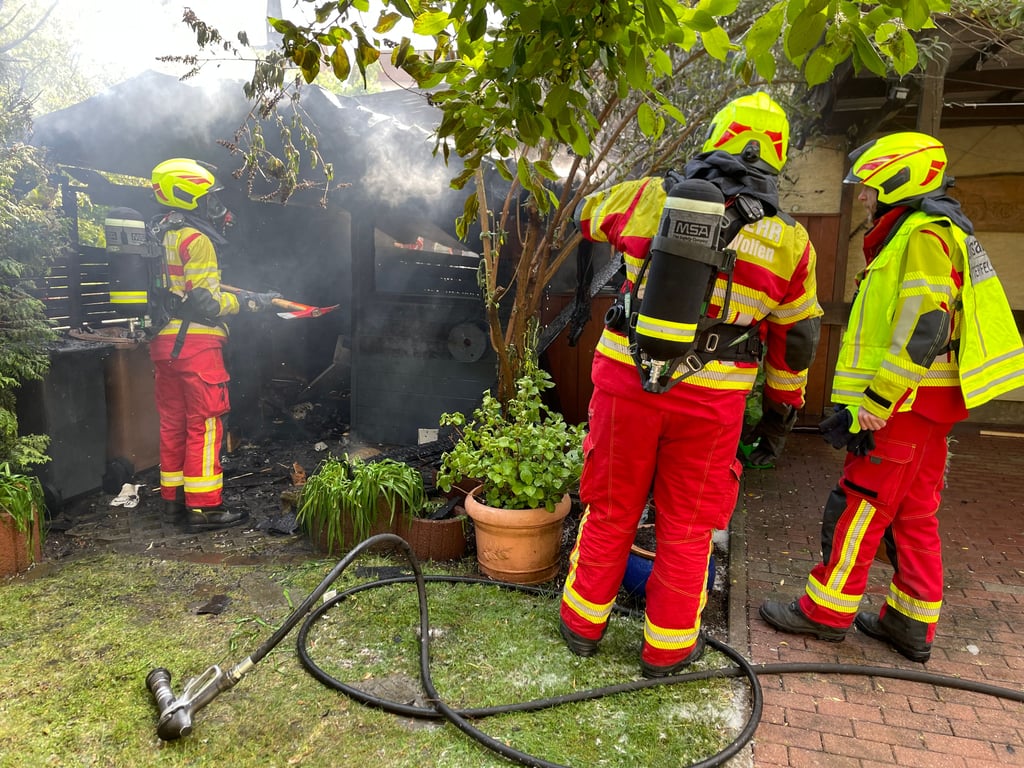 Im Garten des Mehrfamilienhauses löschen die Kameraden den Brand.