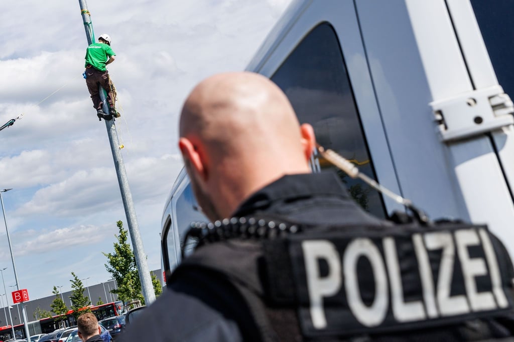 Ein Polizist sperrt den Zugang zu einer Protestaktion gegen den Ausbau des Tesla-Werks in Grünheide.