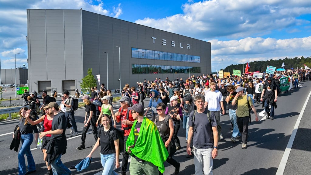 Teilnehmer einer Protestveranstaltung gehen zum Werk von Tesla.