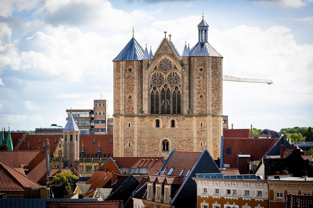Der Braunschweiger Dom ist vor bewölktem Himmel am Horizont zu sehen.