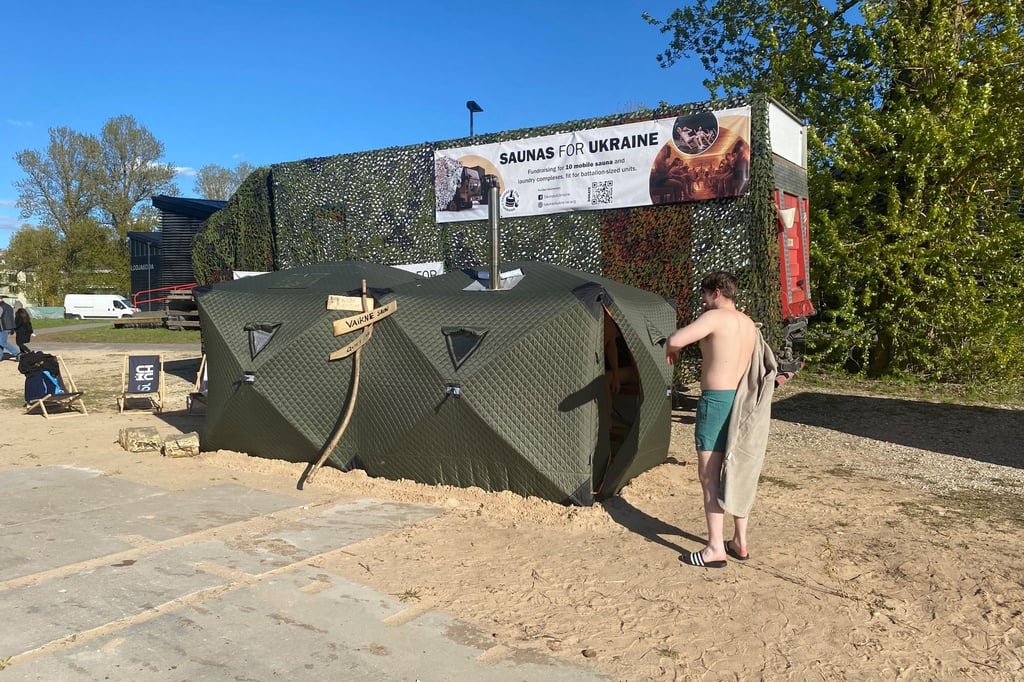 Ein Festival-Besucher steht vor einer mobilen Front-Sauna, die in Estland für die ukrainische Armee entwickelt worden ist.