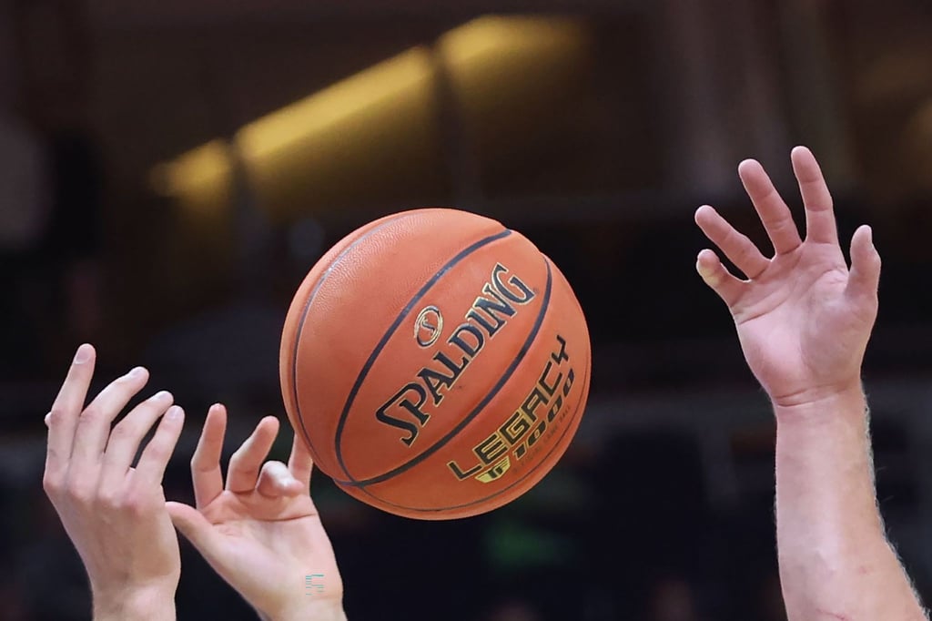 Spieler greifen nach einem Basketball.