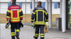 Zwei Feuerwehrmänner laufen auf dem Areal der Landesfeuerwehr- und Katastrophenschutzschule in Nardt entlang.