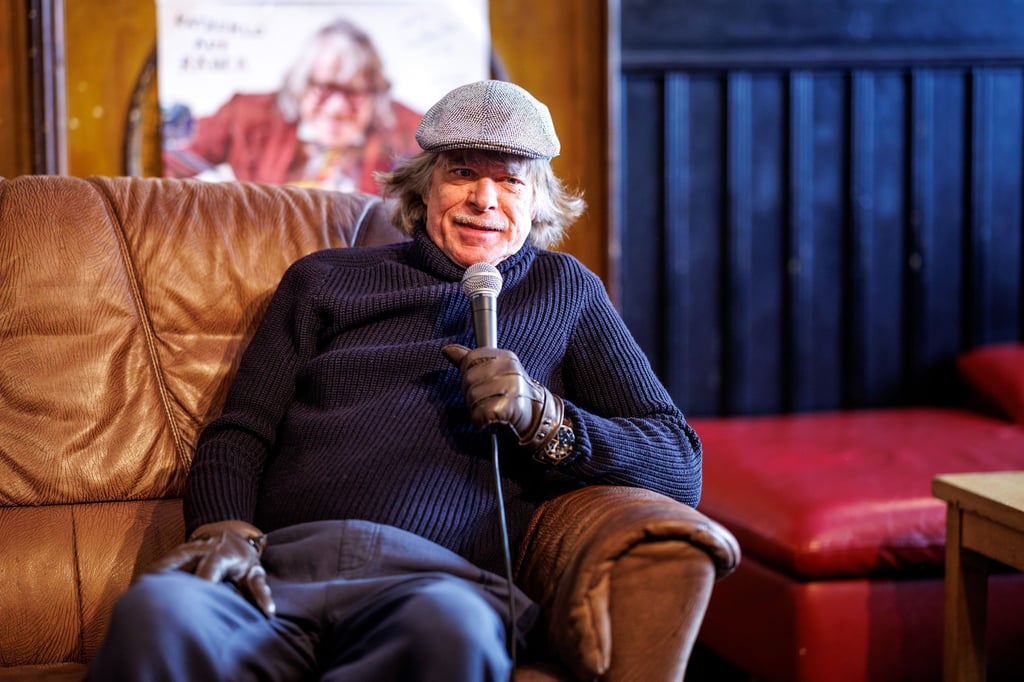 Helge Schneider, deutscher Musiker und Unterhaltungskünstler, sitzt auf einer Pressekonferenz mit dem Titel „Künstliche Intilligens bei Helge“ zu seiner Tournee 2024 „Katzeklo auf Rädern“ im Lustspielhaus in München Schwabing auf einem Sofa.