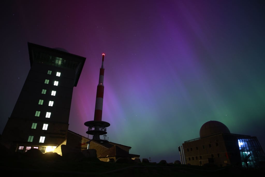 Polarlichter erscheinen über dem Brocken am Nachthimmel.