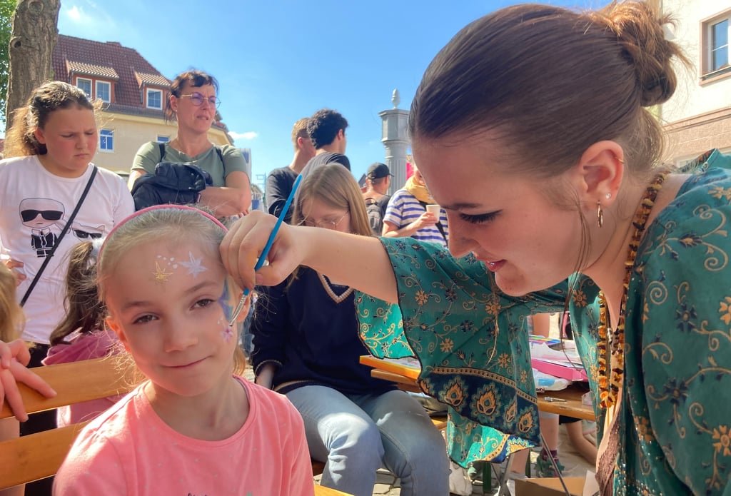 Unter dem Motto "Burg ist bunt" ist am 11. Mai 2024 auf dem Magdalenenplatz in Burgein Straßenfest auf die Beine gestellt worden, das für Vielfalt warb. Hier verziert Lina Hartmann das Gesicht von Besucherin Finja.