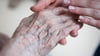 Eine Pflegerin hält die Hand einer Bewohnerin in einem Pflegeheim.