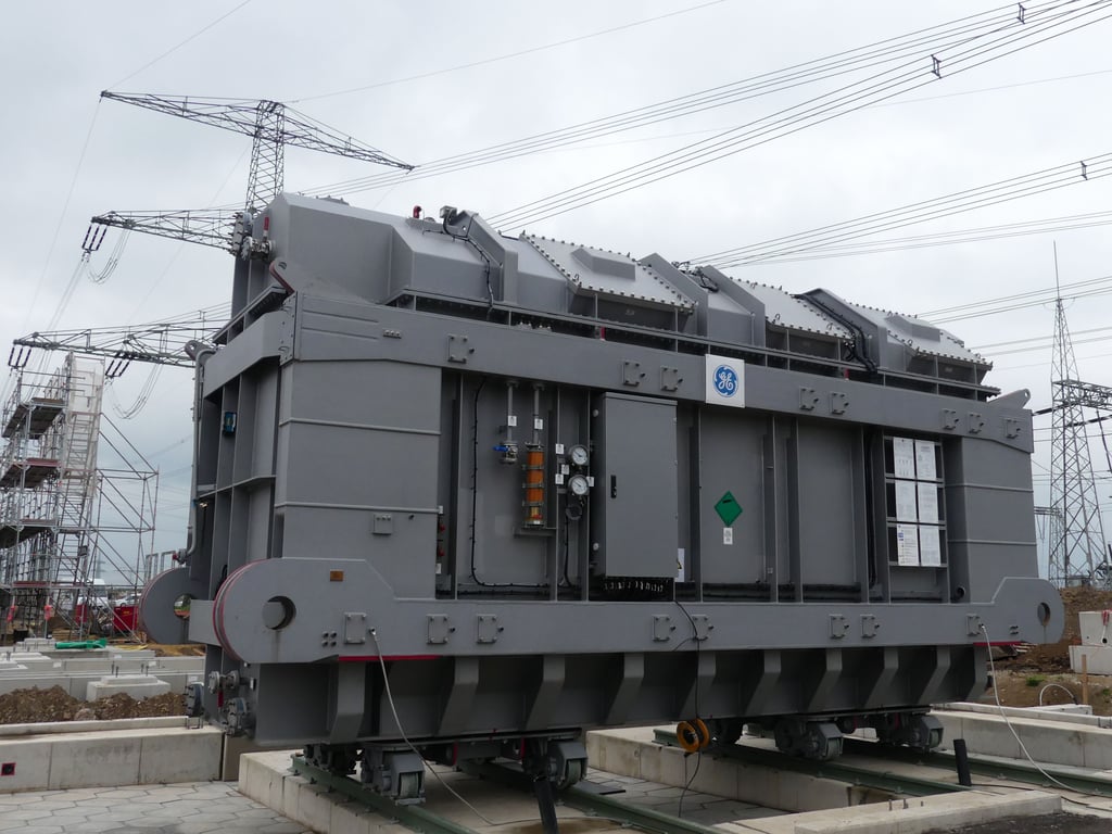 Der erste der 300 Tonnen schweren neuen Transformatoren steht bereits am küntigen Einsatzort. Der Mast dahinter muss noch weichen.