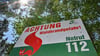 Ein Schild mit der Aufschrift „Achtung Waldbrandgefahr! Notruf 112“ steht vor Bäumen.