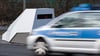 Ein Polizeiwagen fährt an einem mobilen Blitzwagen, einem Geschwindigkeitsmessanhänger der Marke Votronic, vorbei.