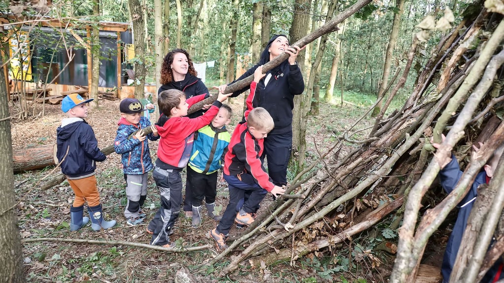 Archivbild - Mit vereinten Kräften baut die Mooswichtelgruppe mit Hilfe der Erzieherinnen Nicole Black und Alexandra Rettig (r.) ein Tipi aus Ästen und Zweigen.