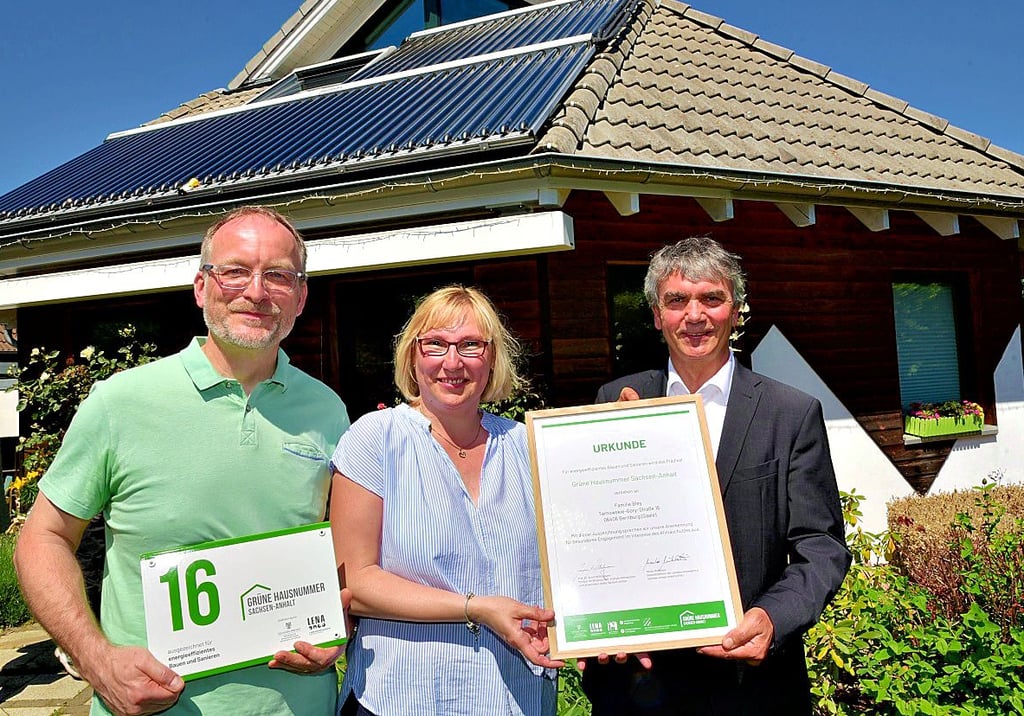 Staatssekretär Steffen Eichner (rechts) übergibt Annett und Mark Bley die erste „Grüne Hausnummer“ in Bernburg.