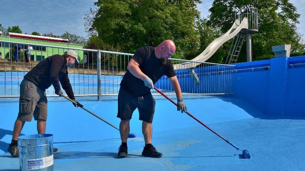 Sebastian Hermann (links) und Tino Strohmeyer streichen gemeinsam mit zahlreichen Nienburgern das Becken des Schwimmbades neu.