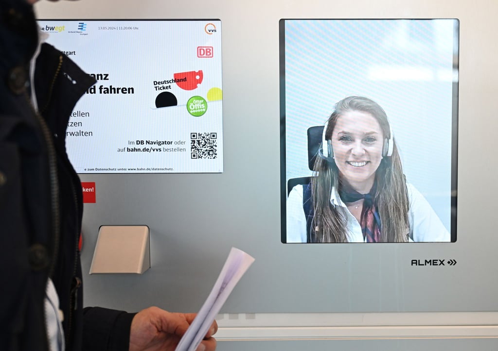 Eine Person steht in einem Video-Reisezentrum und lässt sich per Video persönlich beraten.