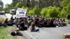 Aktivisten blockieren bei einer Protestaktion gegen Tesla eine Straße. Aktivisten haben am Freitag versucht, auf das Werksgelände von Tesla in Grünheide vorzudringen.
