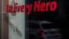Das Logo und der Schriftzug des Essenslieferdienstes Delivery Hero spiegelt sich in einer Scheibe.