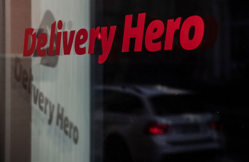 Das Logo und der Schriftzug des Essenslieferdienstes Delivery Hero spiegelt sich in einer Scheibe.