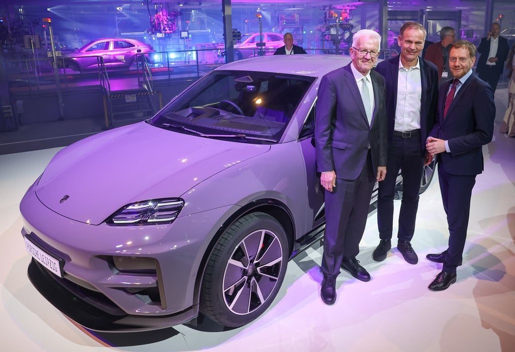Winfried Kretschmann (l-r, Grüne), Ministerpräsident von Baden-Württemberg, Porsche-Chef Oliver Blume und Michael Kretschmer (CDU), Ministerpräsident von Sachsen, stehen zum Produktionsstart neben einem vollelektrischen Porsche Macan im Werk Leipzig.