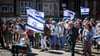 Teilnehmer einer Kundgebung der deutsch-israelischen Gesellschaft Bremen/Unterweser zum Unabhängigkeitstag des Staates Israel stehen mit israelischen Flaggen auf dem Marktplatz in Bremen.